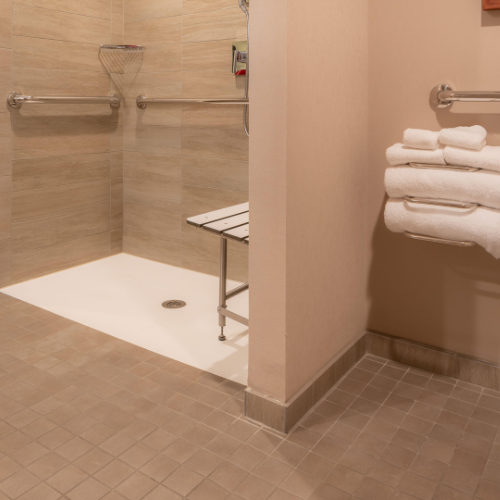 accessible-walk-in-shower-with-horizontal-grab-bars-a-folding-shower-bench-and-towels-on-a-wall-rack-in-a-tiled-bathroom - Fix It-Cincy accessible-walk-in-shower-with-horizontal-grab-bars-a-folding-shower-bench-and-towels-on-a-wall-rack-in-a-tiled-bathroom