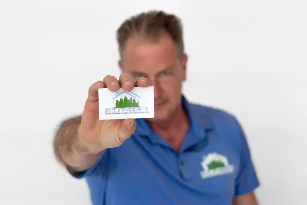 Kevin Delaney holding a Fix It-Cincy business card showing the company logo